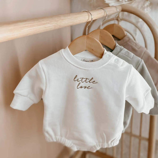 A cozy Little Love Bubble Romper for babies, made from soft fleece-lined cotton in milk color with charming bronze embroidery. The romper features a full sleeve design, O-neck collar, and snap button closures for easy dressing. Ideal for keeping your baby warm and stylish during cooler months.