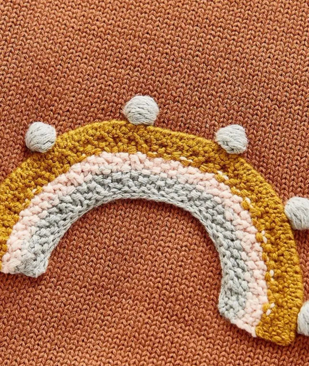 Close-up of rainbow embroidery on baby knit onesie