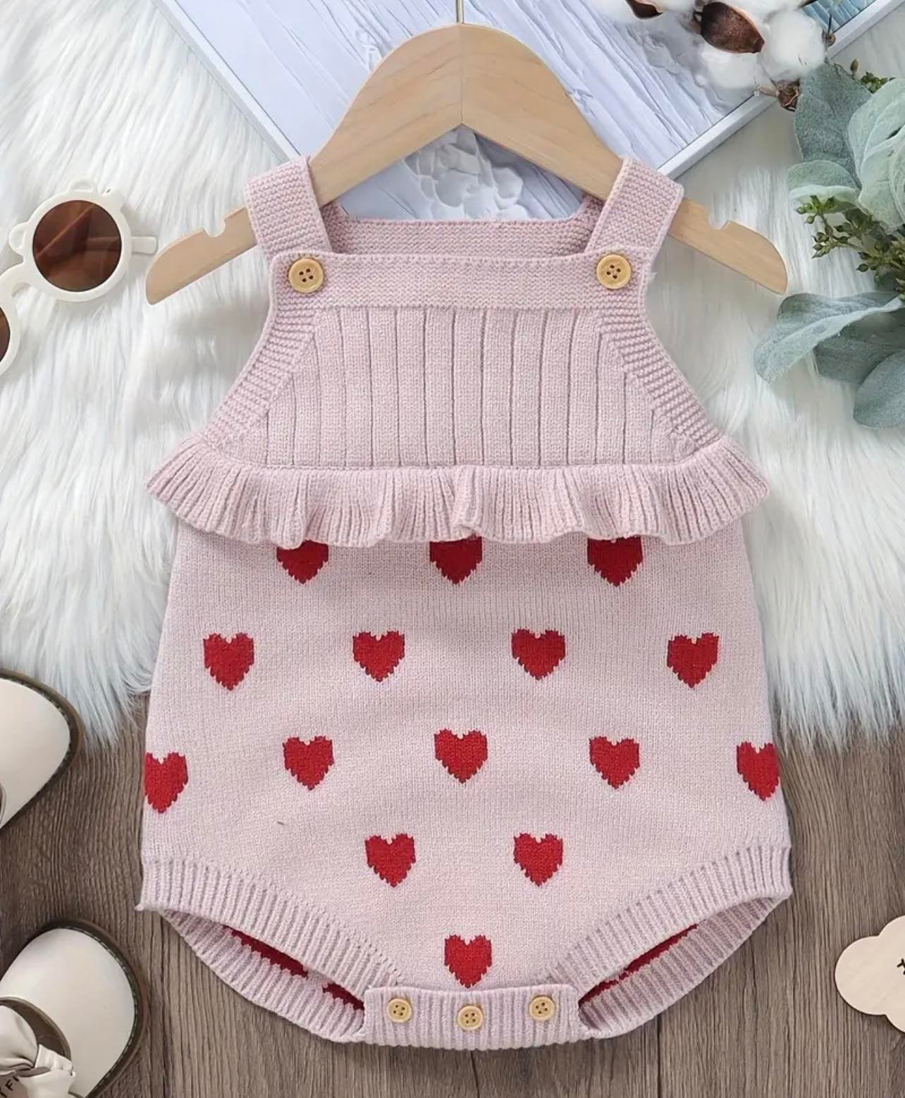 Hearts Jacquard Ruffle Knit Onesie laid flat, showing the detailed heart pattern and ruffle accents