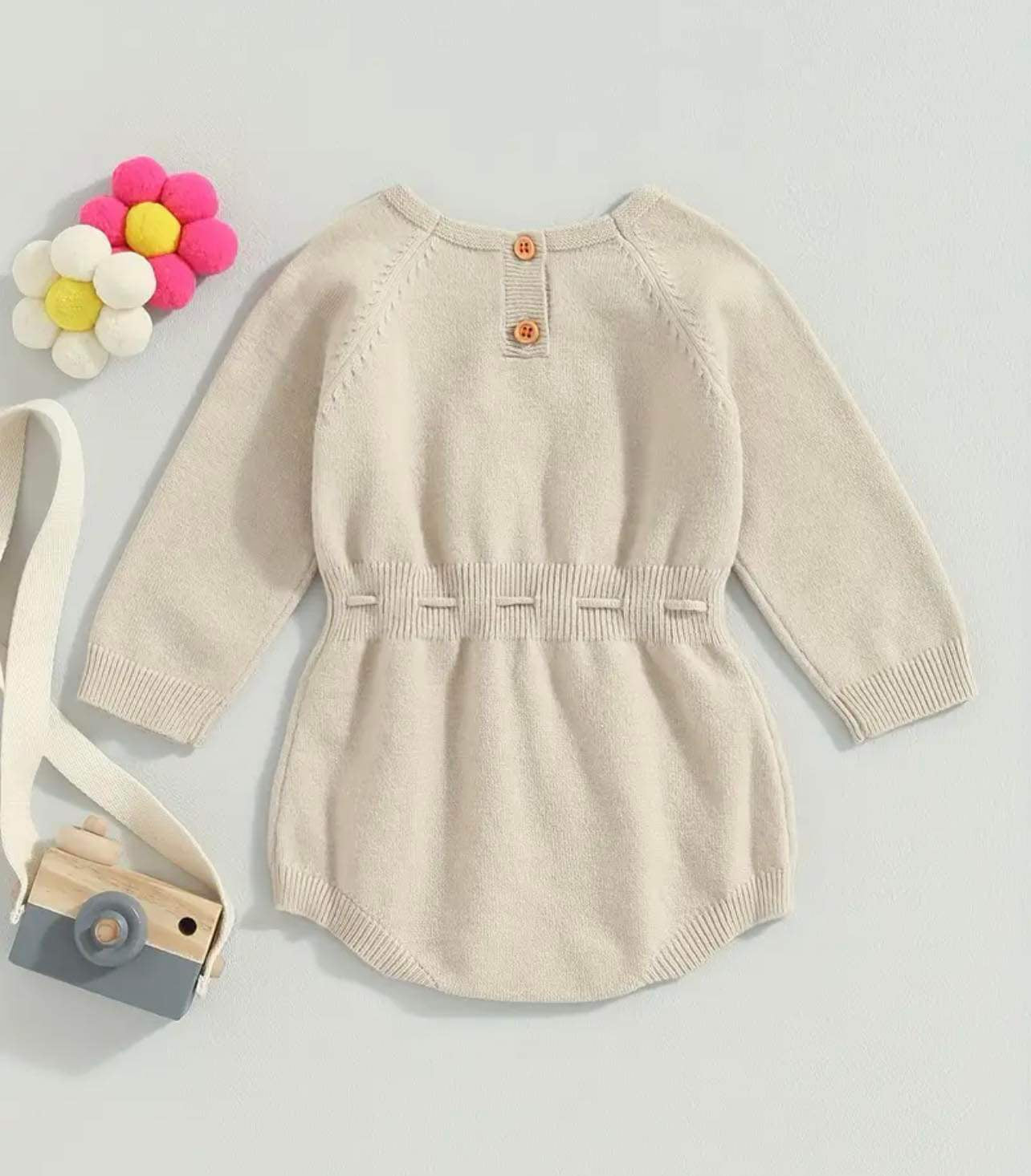 Knitted romper with floral embroidery for babies.