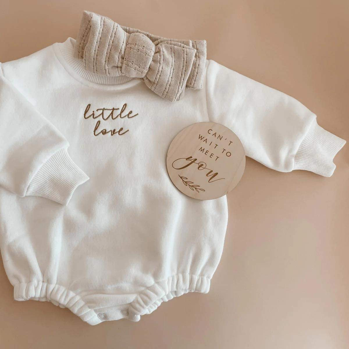 Close-up of the Little Love Bubble Romper showcasing its luxurious fleece-lined cotton material and oversized bronze ‘Little Love’ embroidery. The unisex romper is designed for comfort with full sleeves, an O-neck collar, and convenient snap button closures.