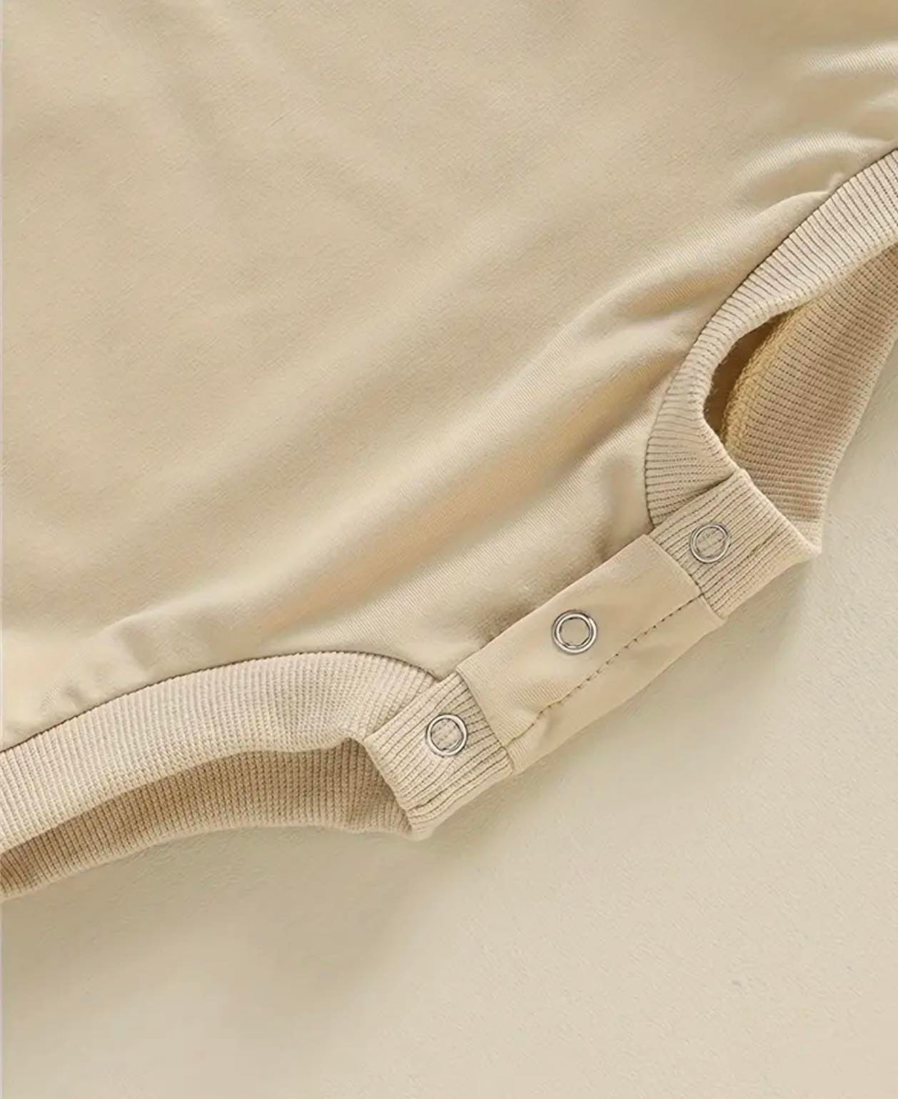 Close-up of the covered button snaps on the 'ONE' Cute Flower Embroidered Romper, ensuring easy dressing and a secure fit for your baby.