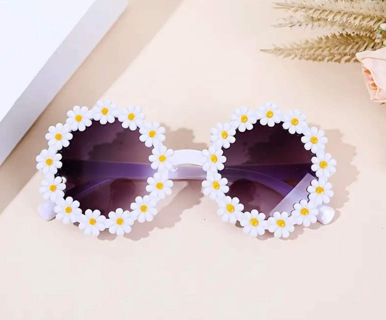 Toddler girl’s daisy sunglasses with playful white flower petal design.