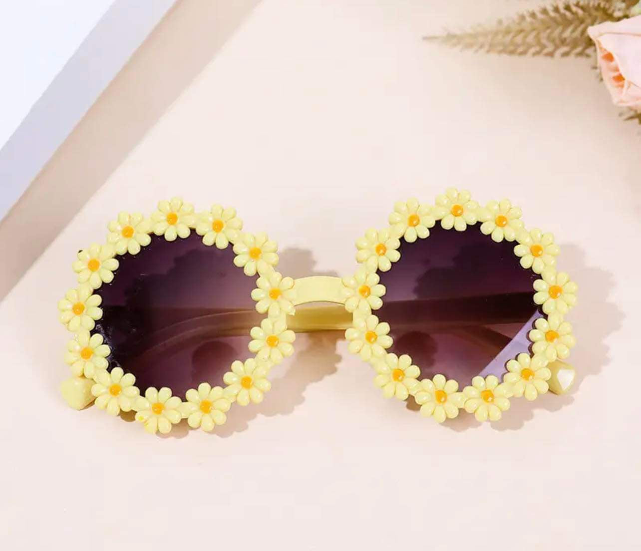 Toddler girl’s daisy sunglasses with playful yellow flower petal design.