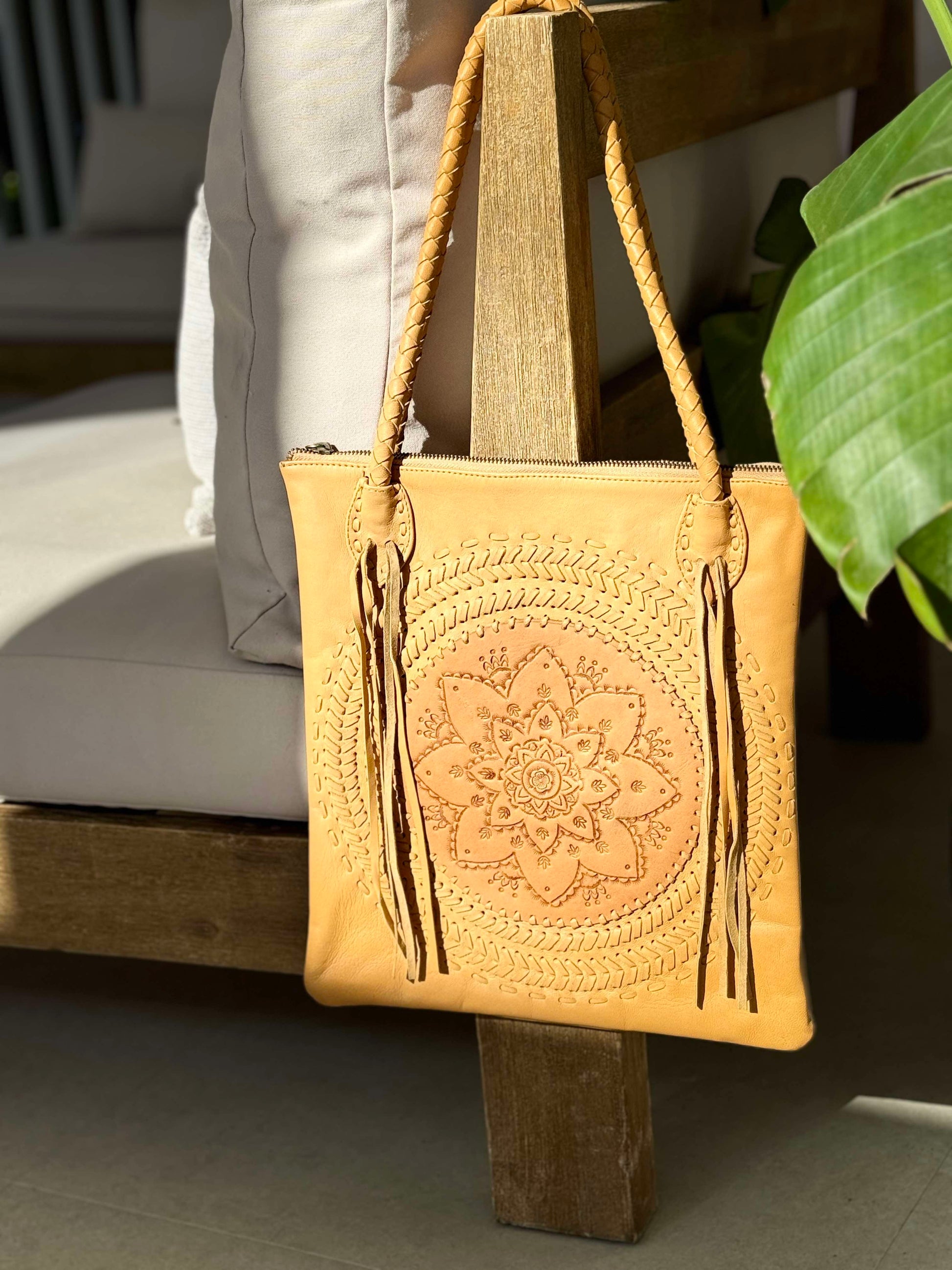 Shop the "Wildflower" hand-tooled leather shoulder bag with fringe and rope handle detailing.